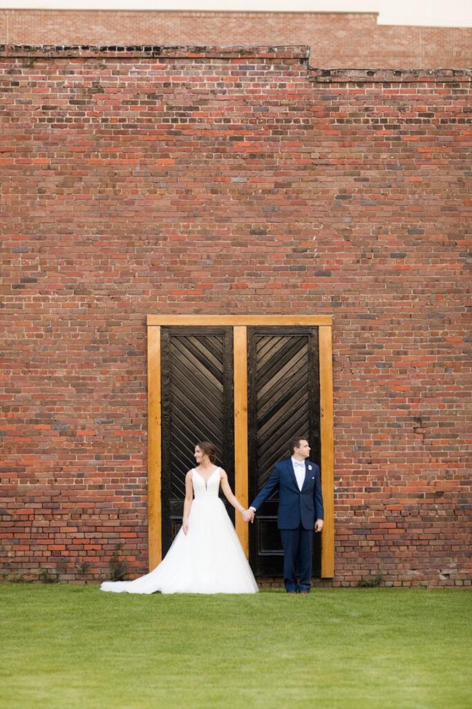 March Couple posing in front of Palafox Wharf Waterfront's iconic black doors after being married at Old Christ Church