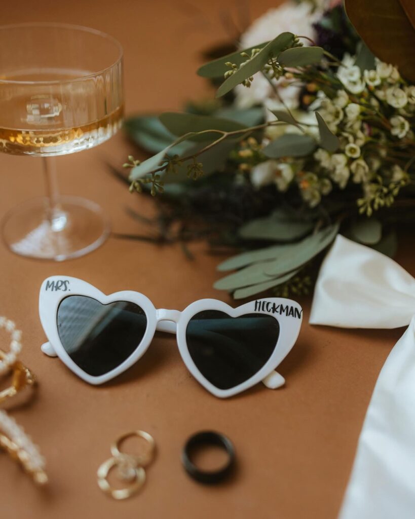 Pensacola wedding places showing palafox wharf wedding couple with rings, sunglasses, champagne glass, bouquet showing real bride wedding