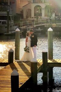 Wedding locations in pensacola fl showing military couple on dock with the waterfront boats and homes with a very scenic background