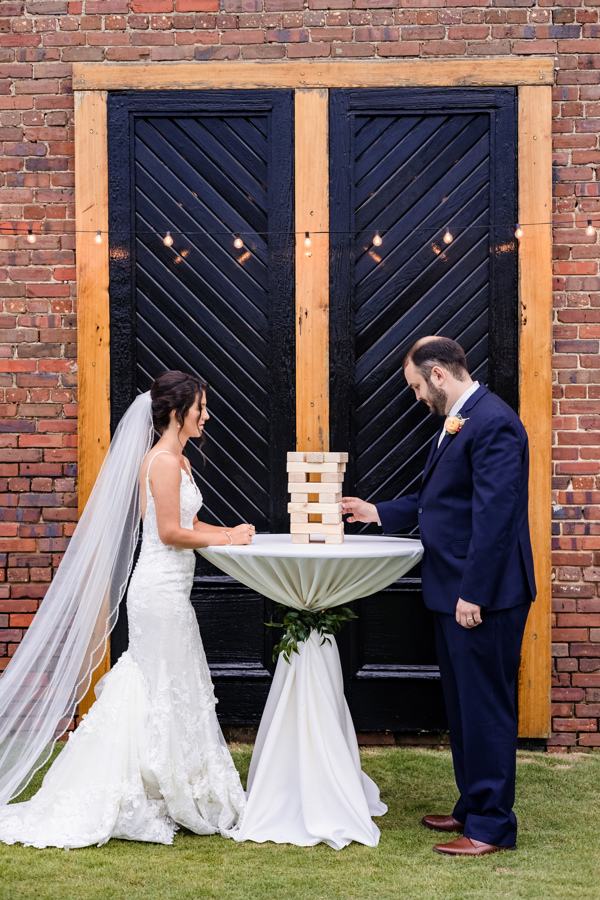 Wedding and Event Destination Bride and Groom, both in the music field, playing games on Palafox Wharf Waterfront's green in front of the icon black doors on the Gulf Coast in Pensacola Florida