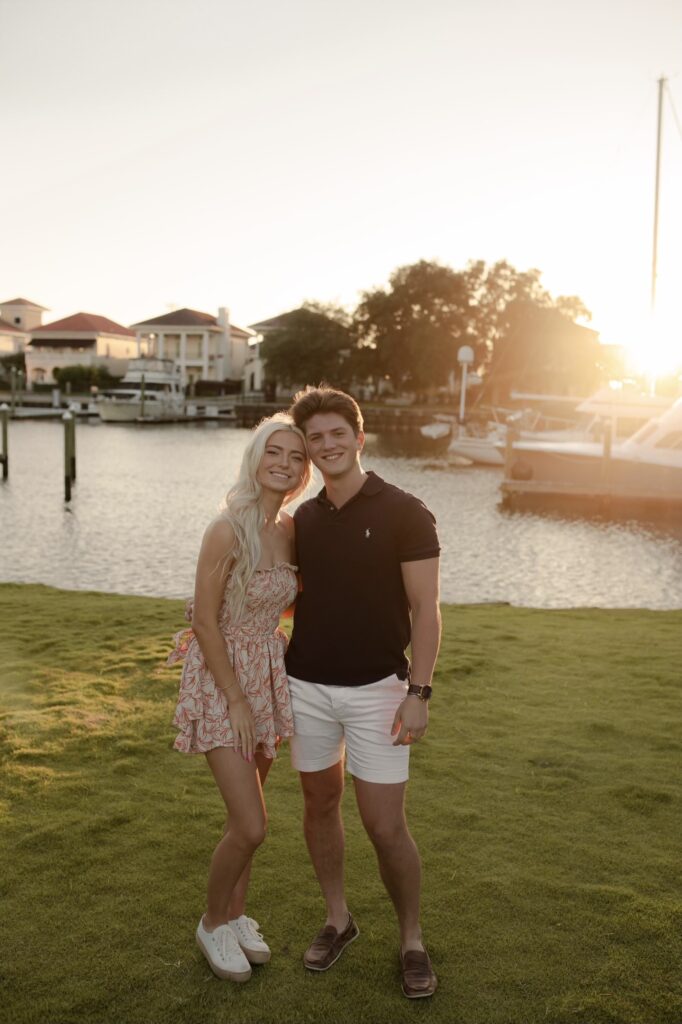 She lives in Pensacola and he is attending NYU on the Palafox Wharf Waterfront Event Venue lawn when the sun is just starting to set.  She is pretty in a floral peachy outfit!