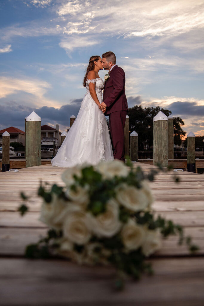 Near Pensacola Florida The Emerald Coast Groom in deep burgundy wedding attire on the dock with bride with florals at Palafox Wharf Waterfront http://tripletfarm1910.com/
