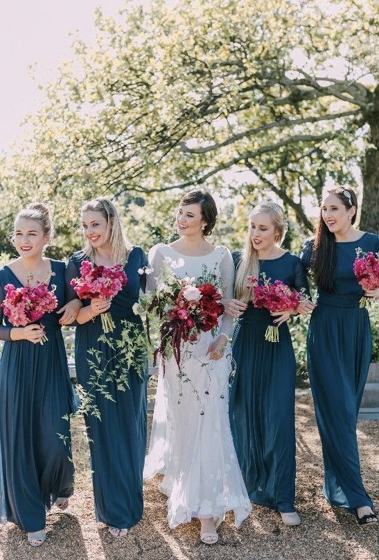 Near Pensacola and Destin this wedding event has beautiful sapphire blue bridesmaid's gowns taking a stroll with bride and carrying striking pink and garnet floral bouquet https://www.highbeamdreams.com/weddings https://landlfarm.com/
