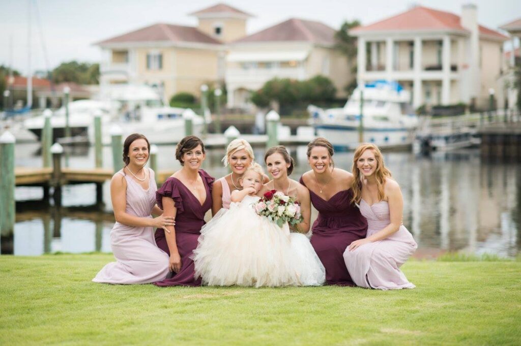 Near Destin and Pensacola Florida showing pretty in pink and burgundy gowns with a very cute Flower Girl on the Waterfront Green at https://617palafoxwharf.com/ 
https://thebellasera.com/
