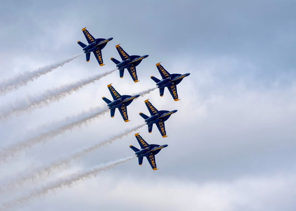 Blue Angels jets flying in formation with trails in the blue sky, near a wedding venue Pensacola.