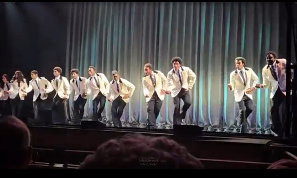 Dancers in white suits performing on stage, near a wedding venue Pensacola FL.