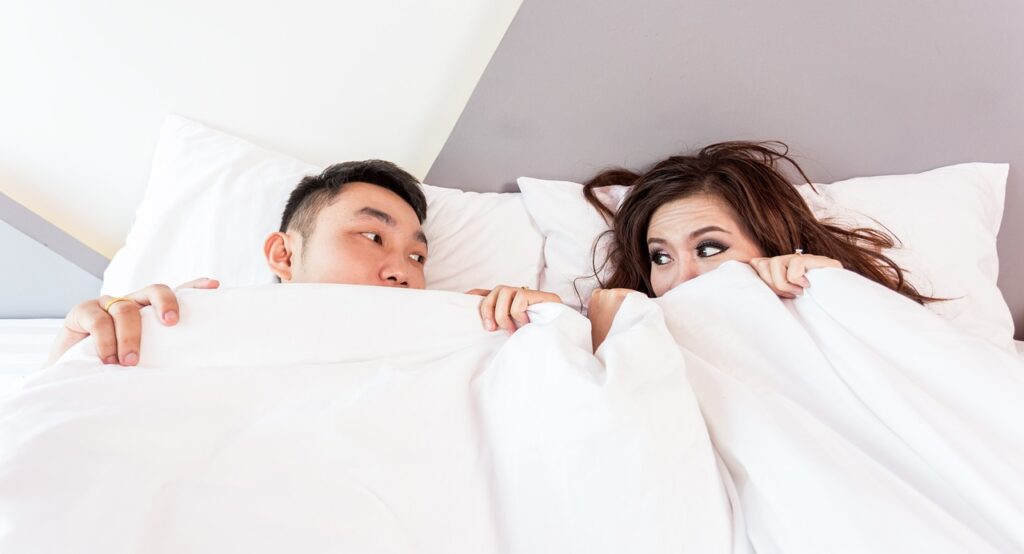 Bride and. Groom under the covers thinking of talking about being a newly engaged couple and needing guidance to buying their first home together https://617palafoxwharf.com/blog/