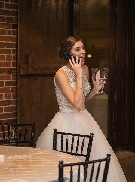 Bride making a call to a love one on the waterfront deck