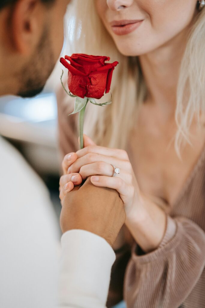 Pensacola event venue near Pensacola near Destin showing bride and groom with single red nose and she is wearing an engagement ring