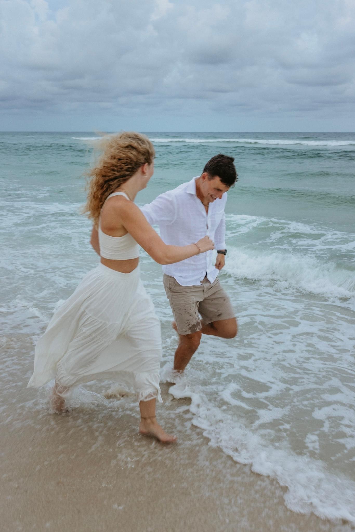 Couple running in water enjoying the pre-wedding exitement