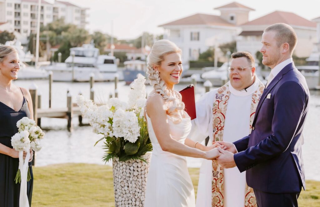 Atlanta Destination couple, Kathleen + Patrick’s Ceremony on the Green at Palafox Waterfront with Maid of Honor and Minister along with scenic backdrop.  Photo by Love is Wild Photography