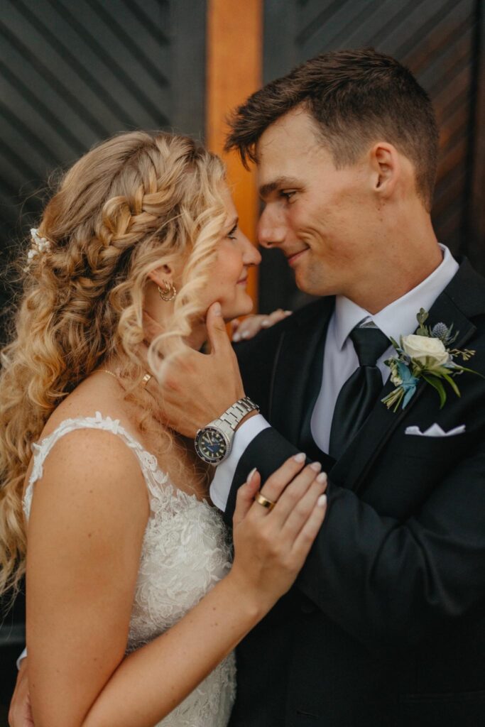 Passionate couple glazing into each other’s eyes with groom tenderly touching bride’s face