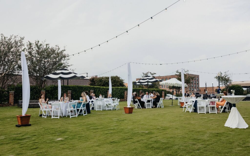 Extended Reception to the Waterfront Lawn with tables, chairs, hi boys, twinkling cafe lights, and umbrellas