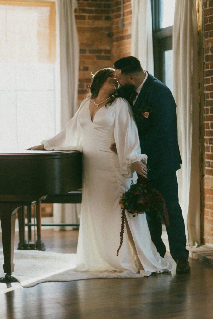 Catie + TJ share a meaningful tender moment in front of a baby grand piano at Catie's accommodations. Photo by Photo by Hayle Wilson Photography