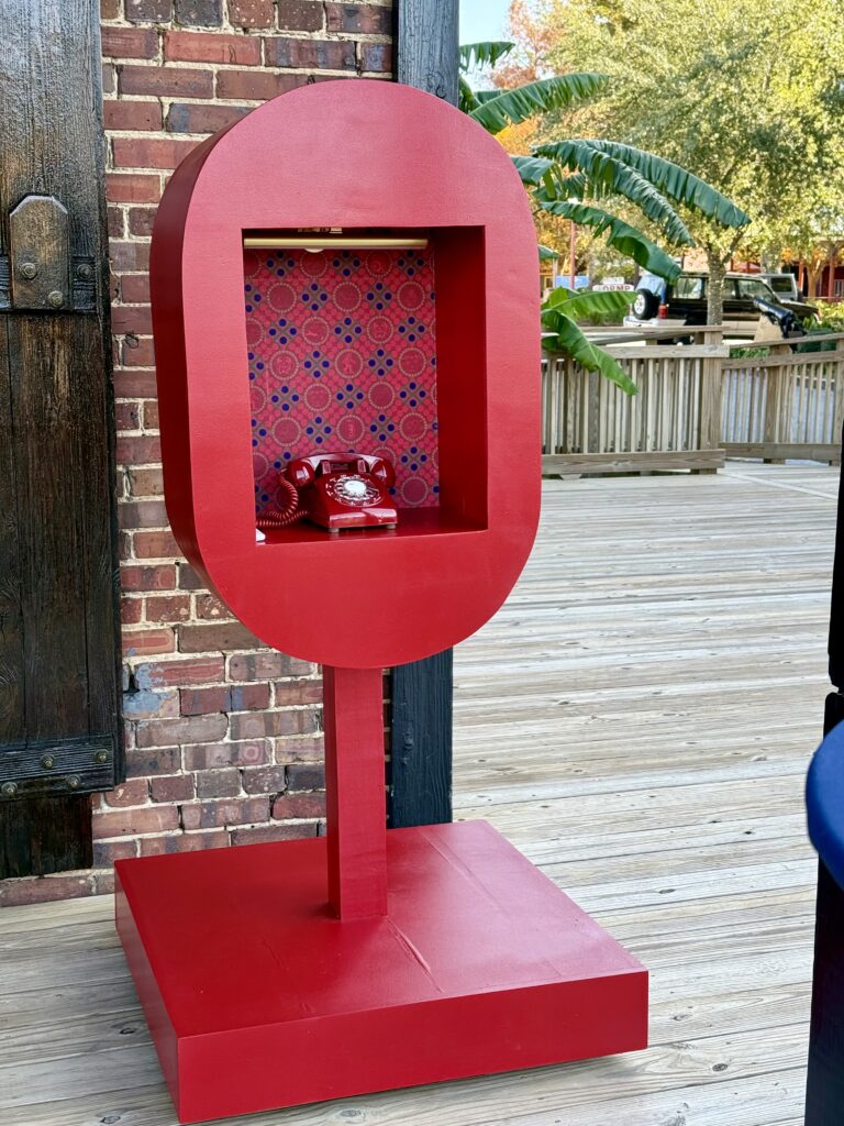 Near Destin, Palafox Wharf Waterfront Venue's couple's handcrafted red phone booth with a tone guest audio book on the waterfront deck for cocktail hour.  This is a great idea anytime including in this stunning fall wedding at Palafox Wharf Waterfront.