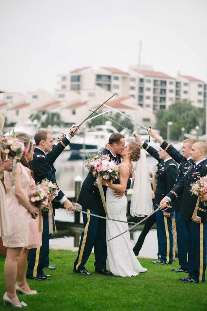 Great example of how to pose for engagement photos.  Wedding Venue called Palafox Wharf Waterfront Wedding Venue showing the Groom with Bridesmaids all smiling looking into the camera leaning against one another at the Palafox Wharf Waterfront Wedding Venue’s Dock.  Photo by Patsy Brown Photography