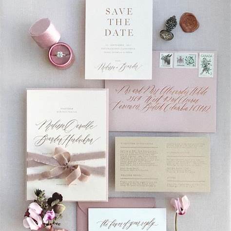 Pink flat lay of invitation suite with engagement find, stamp and florls