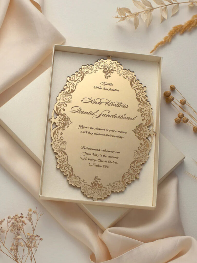 One of the Best Wedding Venues Pensacola Fl is Palafox Wharf Waterfront Wedding Venue showing here a gorgeous hand engraved wedding invitation in a presentation box laying on blush satin and brown detailed branches