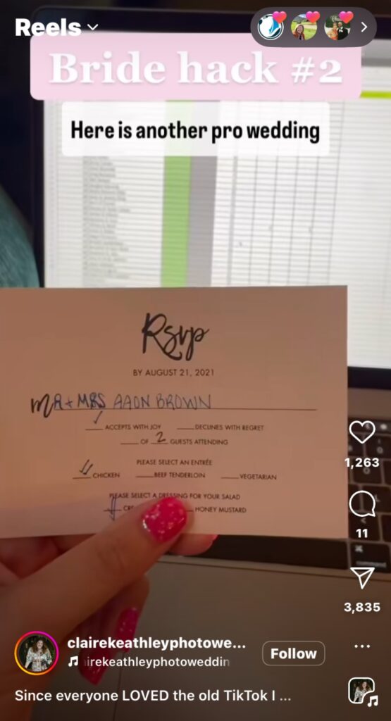 Front side of RSVP showing Name, amount of guests, Meal choice, held by person with red finger nail polish with a computer screen in the background.