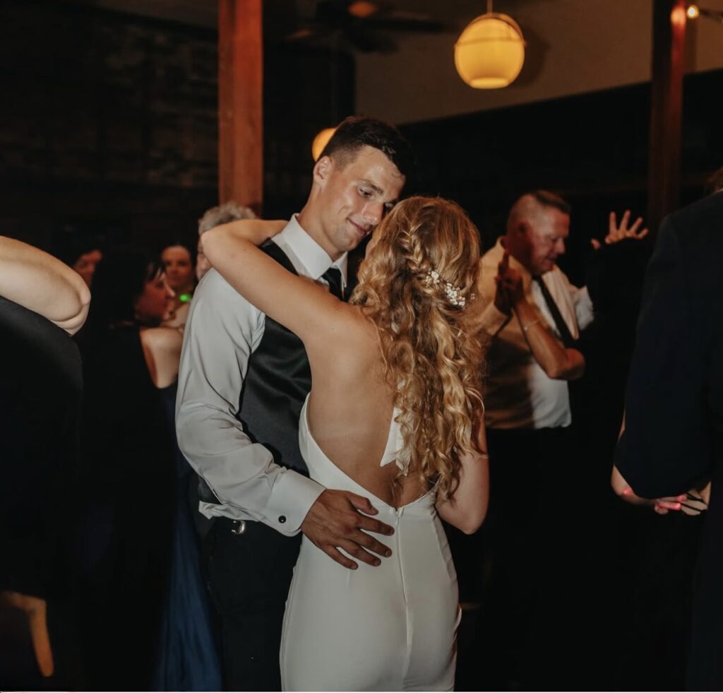 Pensacola wedding venues on the beach with Palafox Wharf Waterfront Wedding Venue Downtown Pensacola on the Water showing mean full smile with love looking at his bride who is in her second wedding dress for dancing at on the dance floor inside Palafox Wharf Waterfront in Pensacola FL