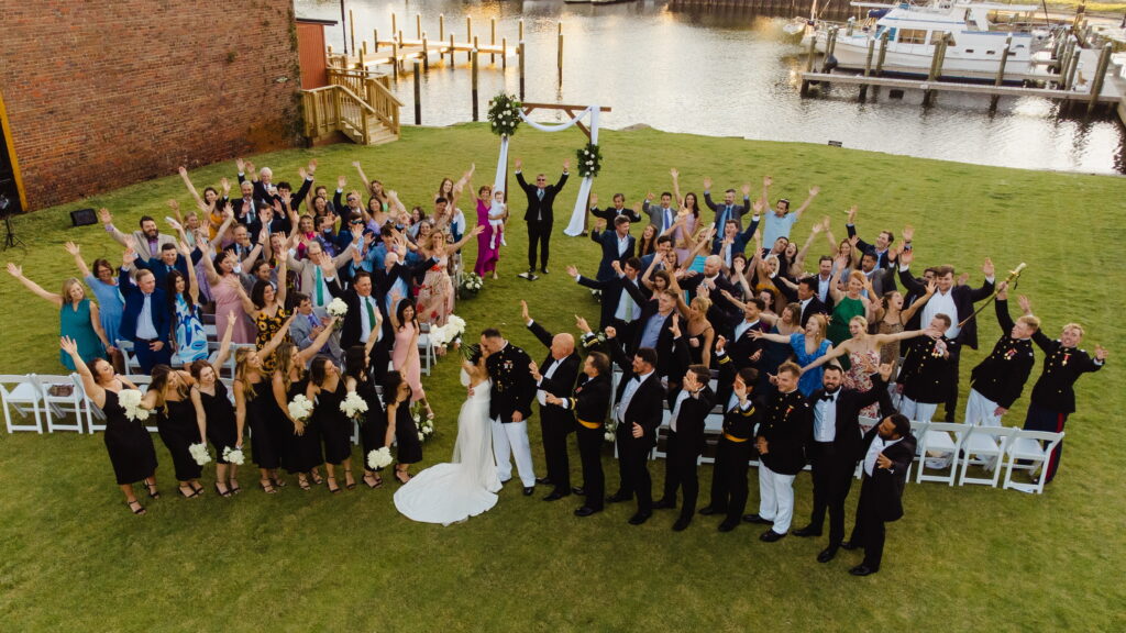 Engaged Couples Can't Get Enough of this Dreamy Southern Downtown Waterfront Wedding Venue Showing a group photo of Ceremony on the waterfront green with Amy and groom with everyone waving 