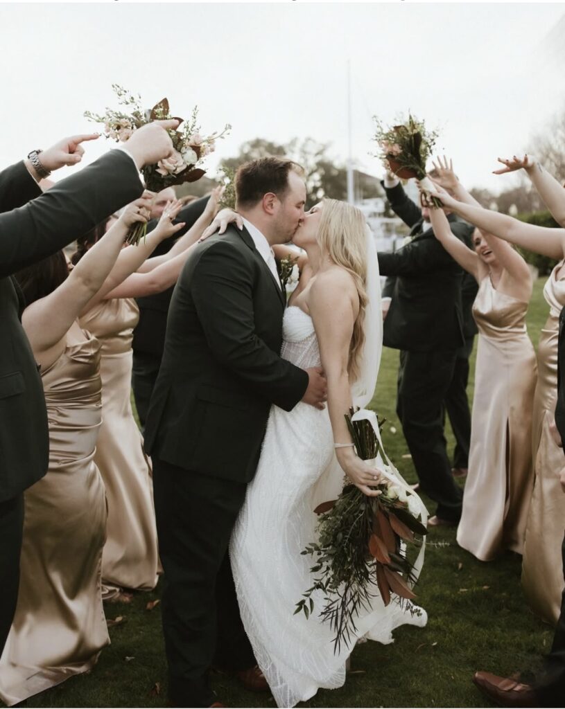 wedding venues pensacola fl  with palafox wharf waterfront wedding venue's couple on the waterfront green with the wedding party formed into a line that the bride and groom are going through and stop for a kiss