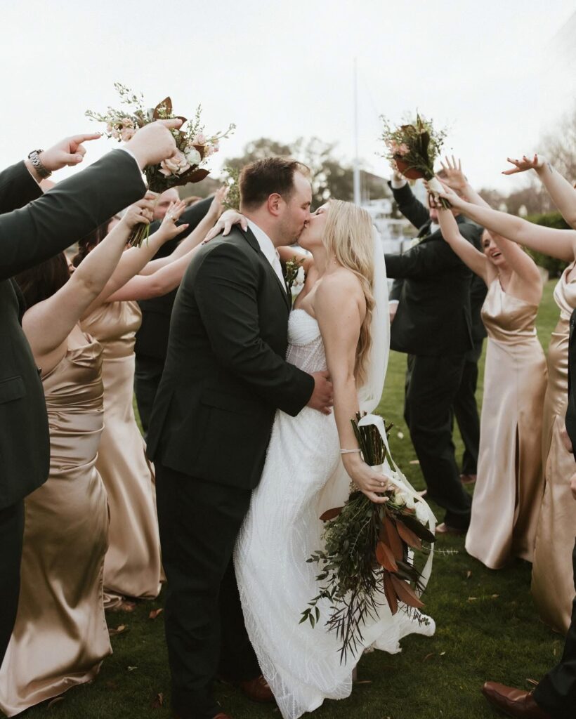 Wedding Venue Pensacola showing  just married couple kissing as they are going through a tunnel of the wedding