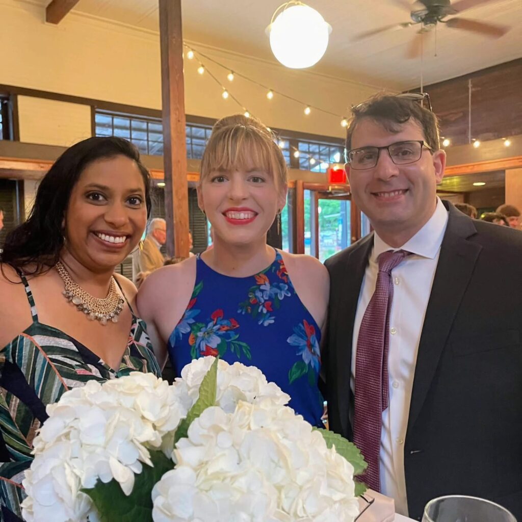 Wedding Venue Pensacola showing guests at a Wedding Celebration for their fellow doctors having been married Showing 3 guests in front of a white floral arrangement