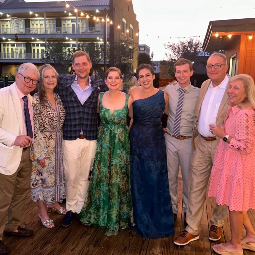 Wedding Venue Pensacola showing guests at a Wedding Celebration for their fellow doctors having been married With a group hugging on the waterfront deck