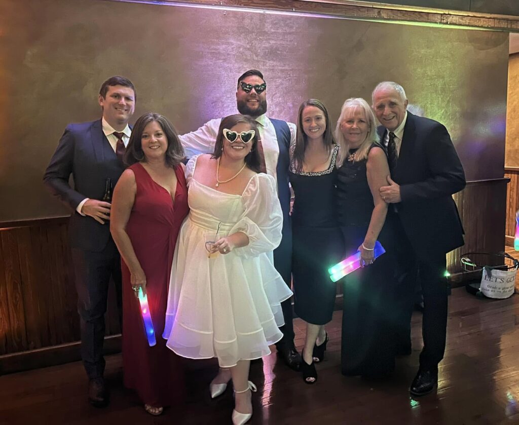 Bride, groom and friends for a photo before leaving for the grand exit with the couple in heart shaped glasses and holding glow wands