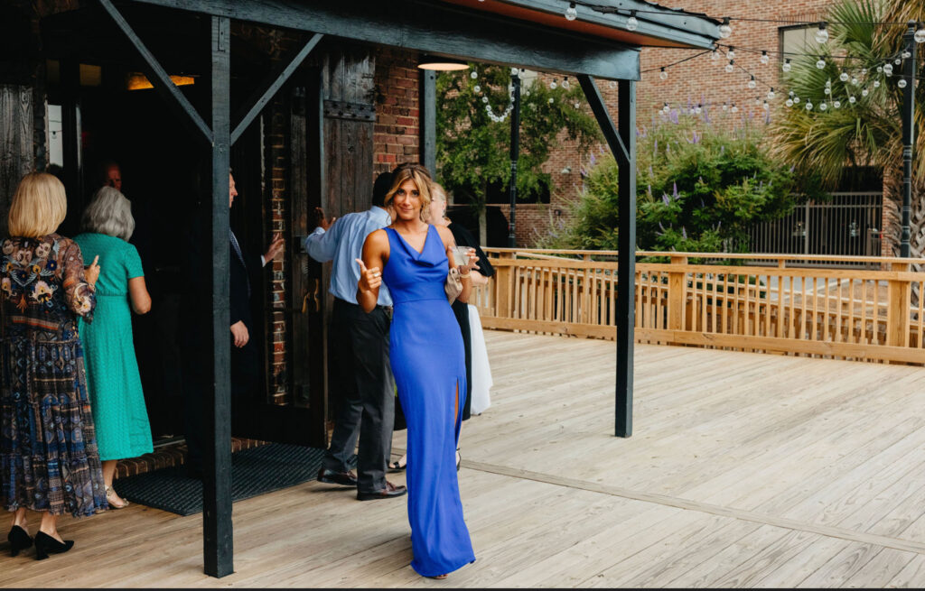 Bridesmaid in a blue outfit on the waterfront deck at Palafox Wharf Waterfront wedding venue