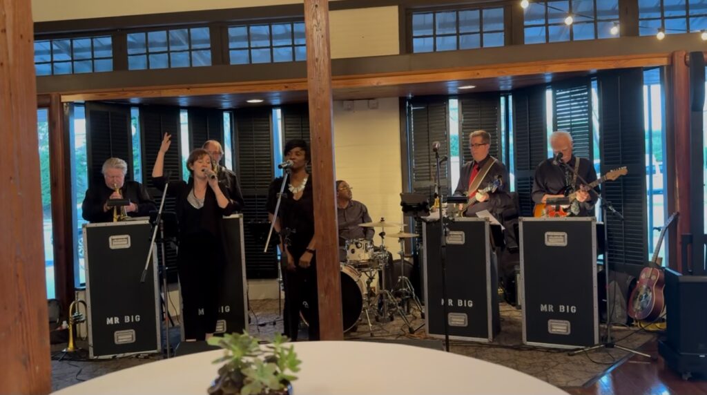 8 piece band in the middle alcove at Palafox Wharf Waterfront Wedding Venue joyfully singing for the guests