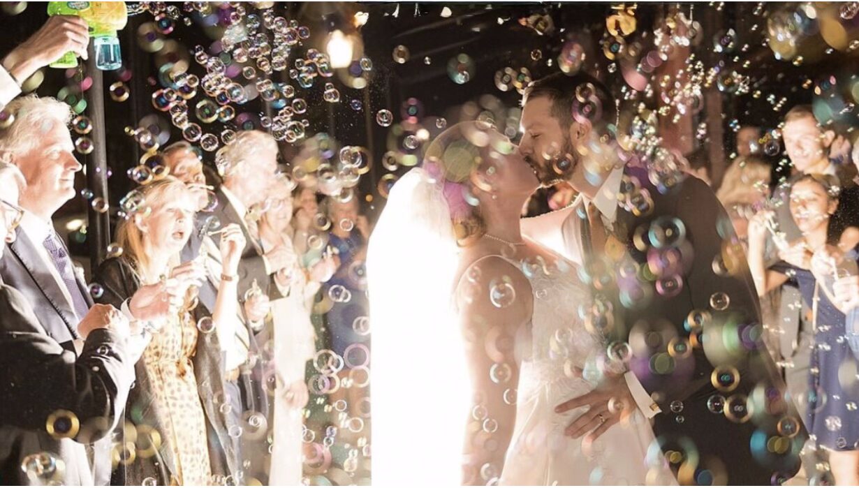 unforgettable wedding guest experience Showing couple with a million colorful bubbles for their Great Exit