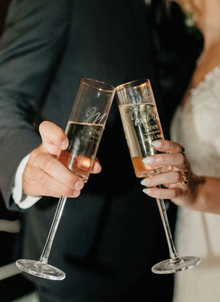 Palafox Wharf Waterfront Wedding Venue with groom and bride holding champagne glasses toasting and he is in black and she is in white