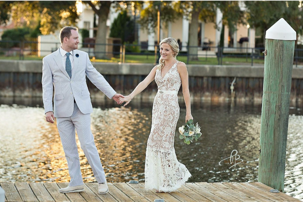 Pensacola wedding venues with a doctor groom and medical bride on the dock with water in the background and a touch of the golden hour reflecting on the water