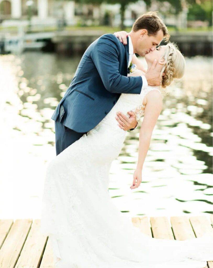 Wedding venues pensacola fl showing groom tenderly kissing bride with sparkling water in the background