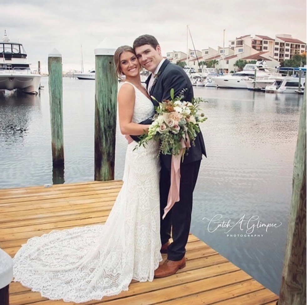 Wedding venues pensacola fl with bride and groom smiling and they are standing on the dock, the T portion of the dock, embracing with the pretty boats and homes in the background
