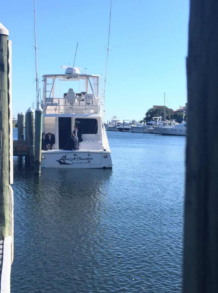 Downtown wedding venue with Blue water showing white boat with groomsmen on it at palafox wharf waterfront wedding venue pensacola fl
