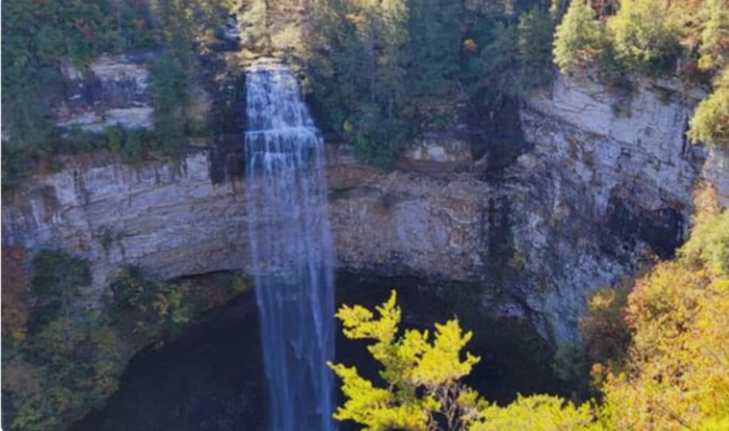 Romantic road trips featuring a stunning waterfall during a southeastern US adventure, with a couple coming to see Pensacola wedding venues, specifically Palafox Wharf Waterfront Wedding Venue, captured in this breathtaking photo of cascading water surrounded by lush forest.

