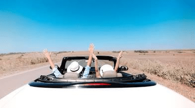 Romantic road trips with stunning views, featuring a couple enjoying an open-top car ride, perfect for exploring wedding places in Pensacola FL and the start of their journey after just becoming engaged.