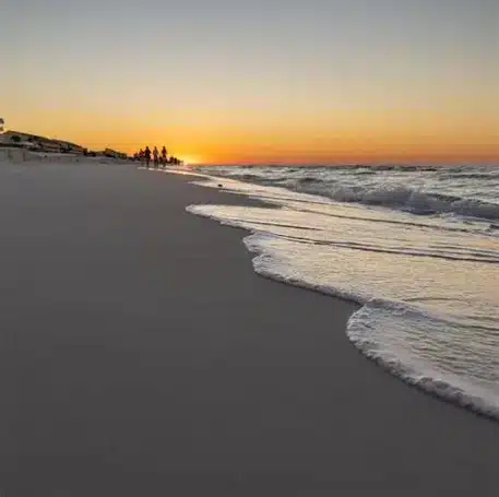 Romantic Date Ideas in Destin Florida with Sunset beach scene waves splashing in shallow water.
