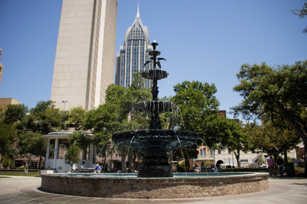 Sunny day at Bienville Square: historic fountain with oak trees and RSA tower—perfect outdoor wedding spot near Pensacola. 52 Amazing Date Ideas in Mobile