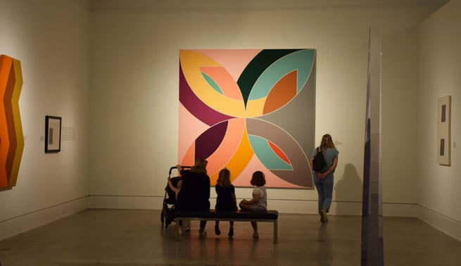 Colorful abstract art exhibit at a top museum in Mobile, AL that a couple went to after seeing wedding places in Pensacola FL, folks admiring the vibrant display.