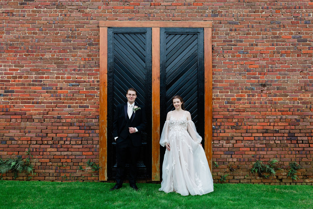 family owned wedding venue with couple standing in front of black doors