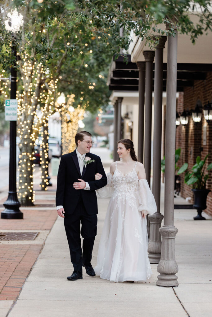 wedding venue pensacola with couple walking with string lights in trees